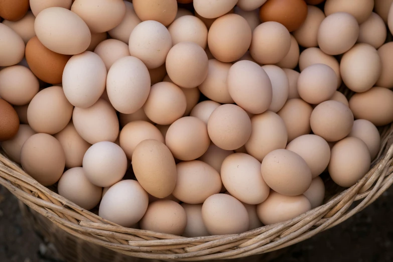 many brown and white eggs sit in a basket