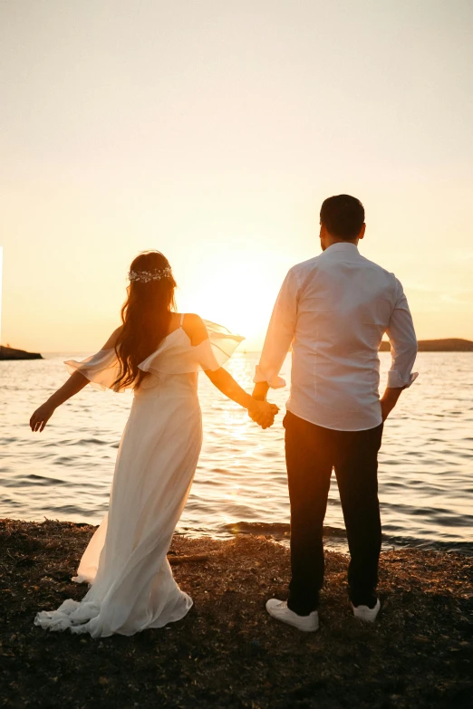 a couple standing next to the ocean on a beach