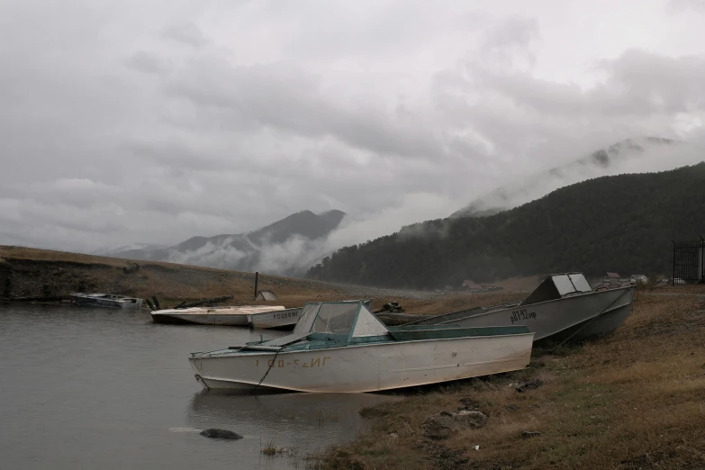 an abandoned boat sitting in the water near a mountain range