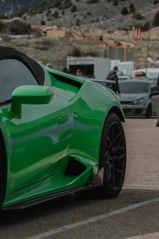 a green sports car parked in a parking lot next to other cars