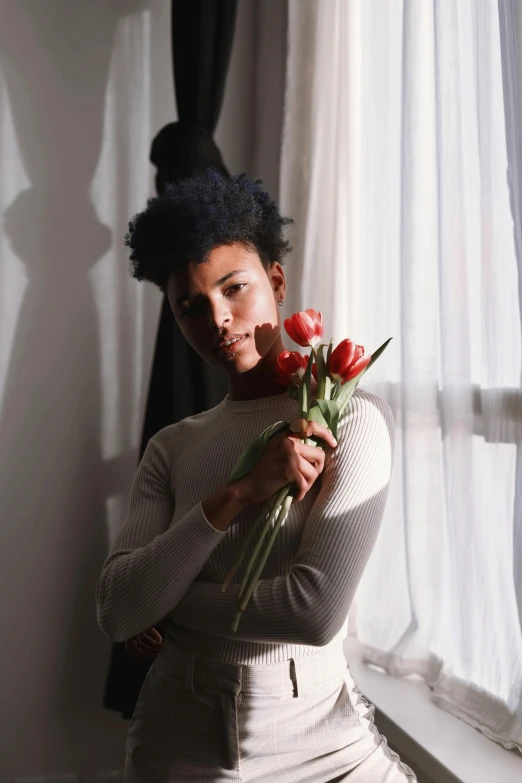 the young woman is holding some red flowers