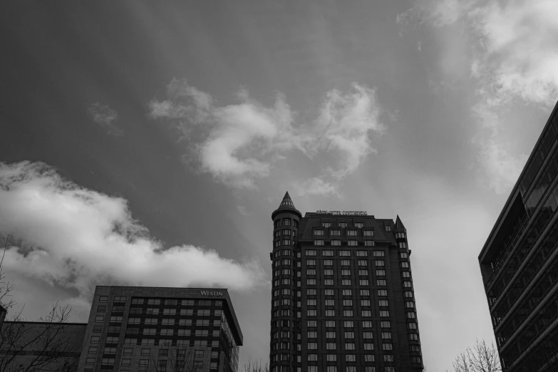 looking up at tall buildings and clouds in the sky