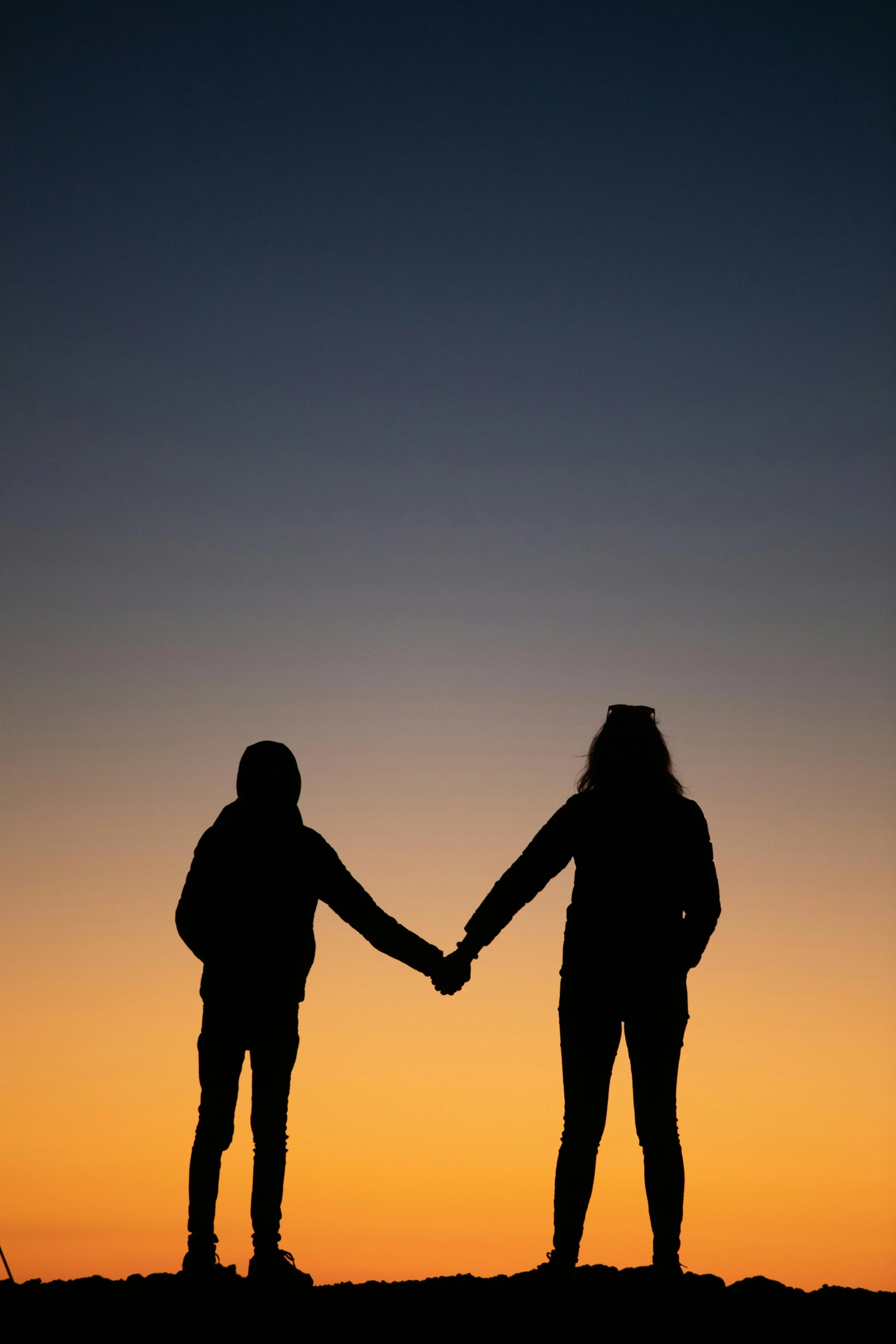 two people holding hands, both with backpacks on their backs