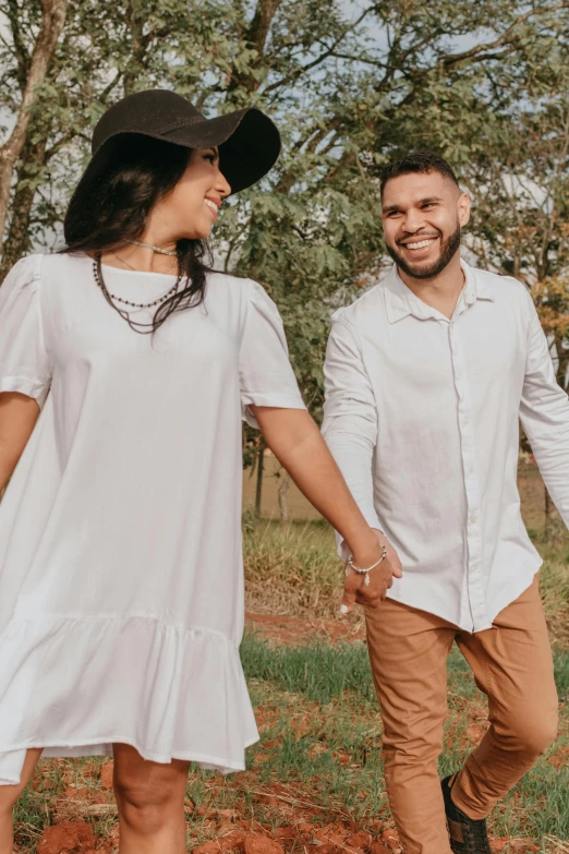 two people in white outfits hold hands and walk through a forest