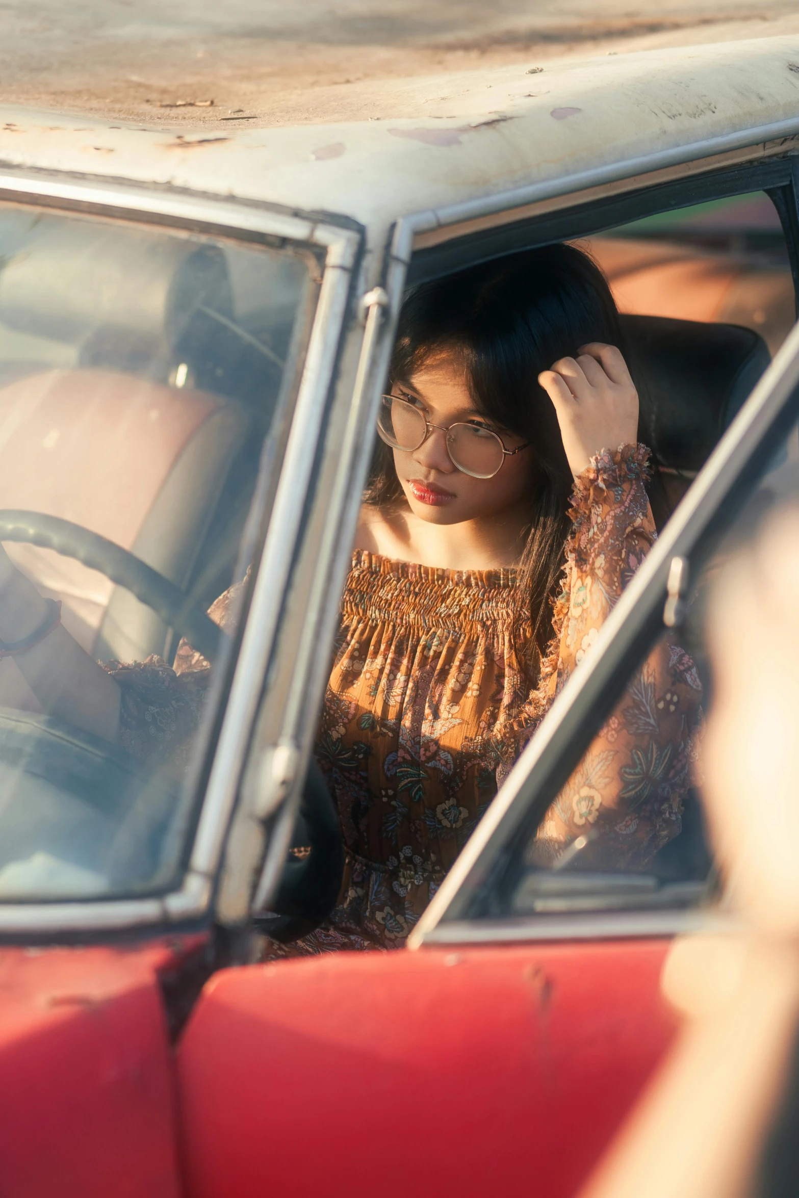 a young woman wearing glasses inside a car looking in the mirror