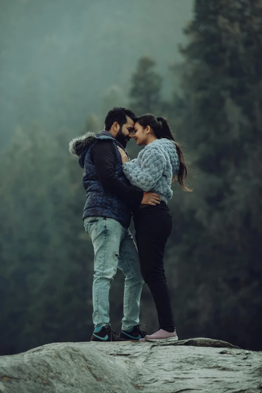 the couple is emcing on top of a rock