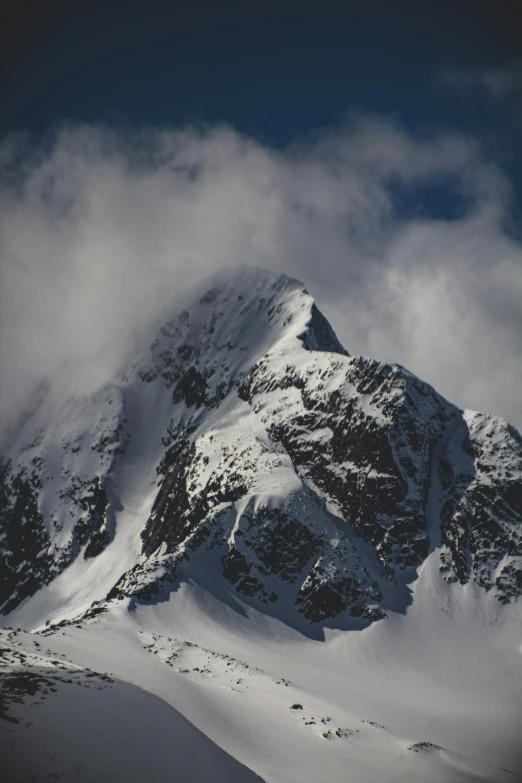 a snow covered mountain in the distance with clouds coming from it