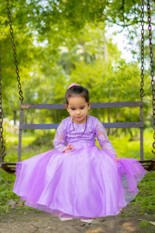 little girl in purple on a swing at the park