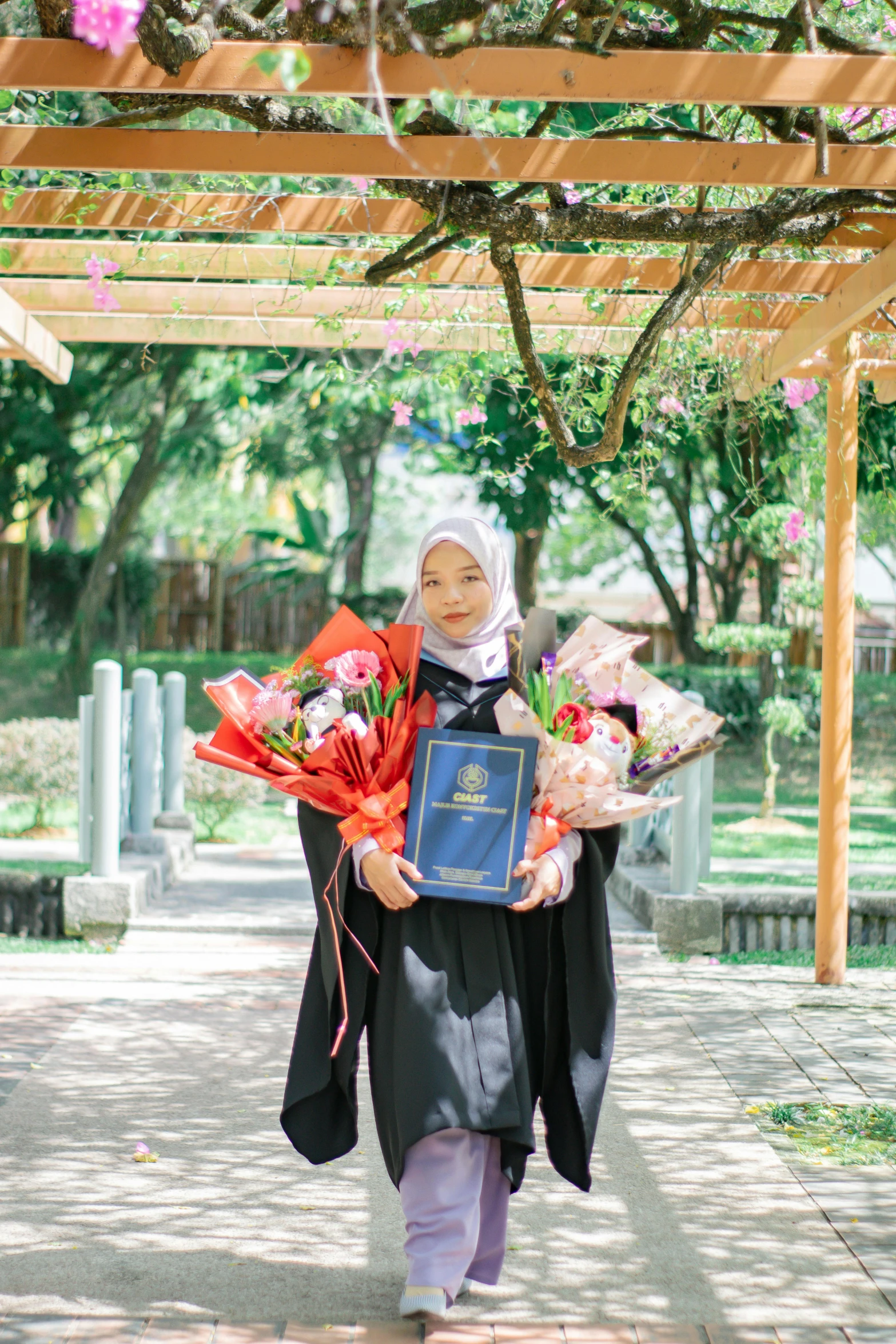 a woman in hijab carrying flowers and an award