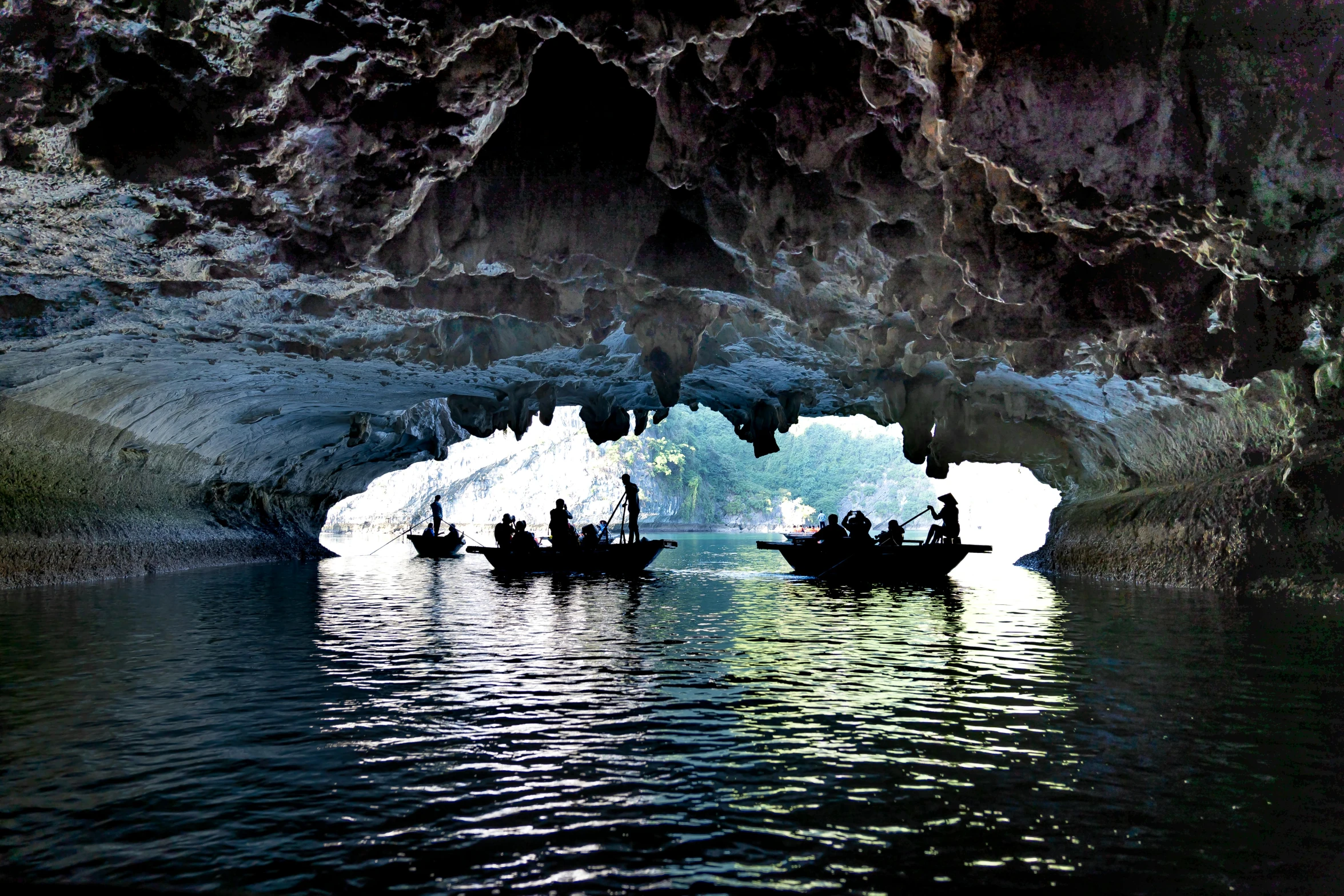 two boats in front of a group of people sitting inside a ice cave