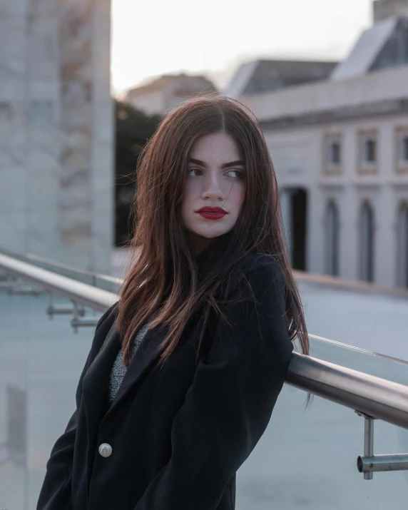 a woman standing near a railing wearing a black blazer