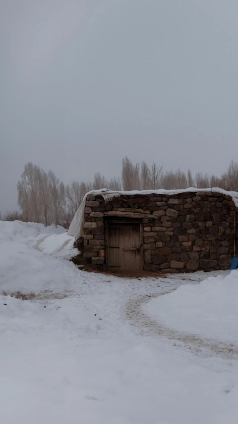 an old cabin on the edge of a snow covered field