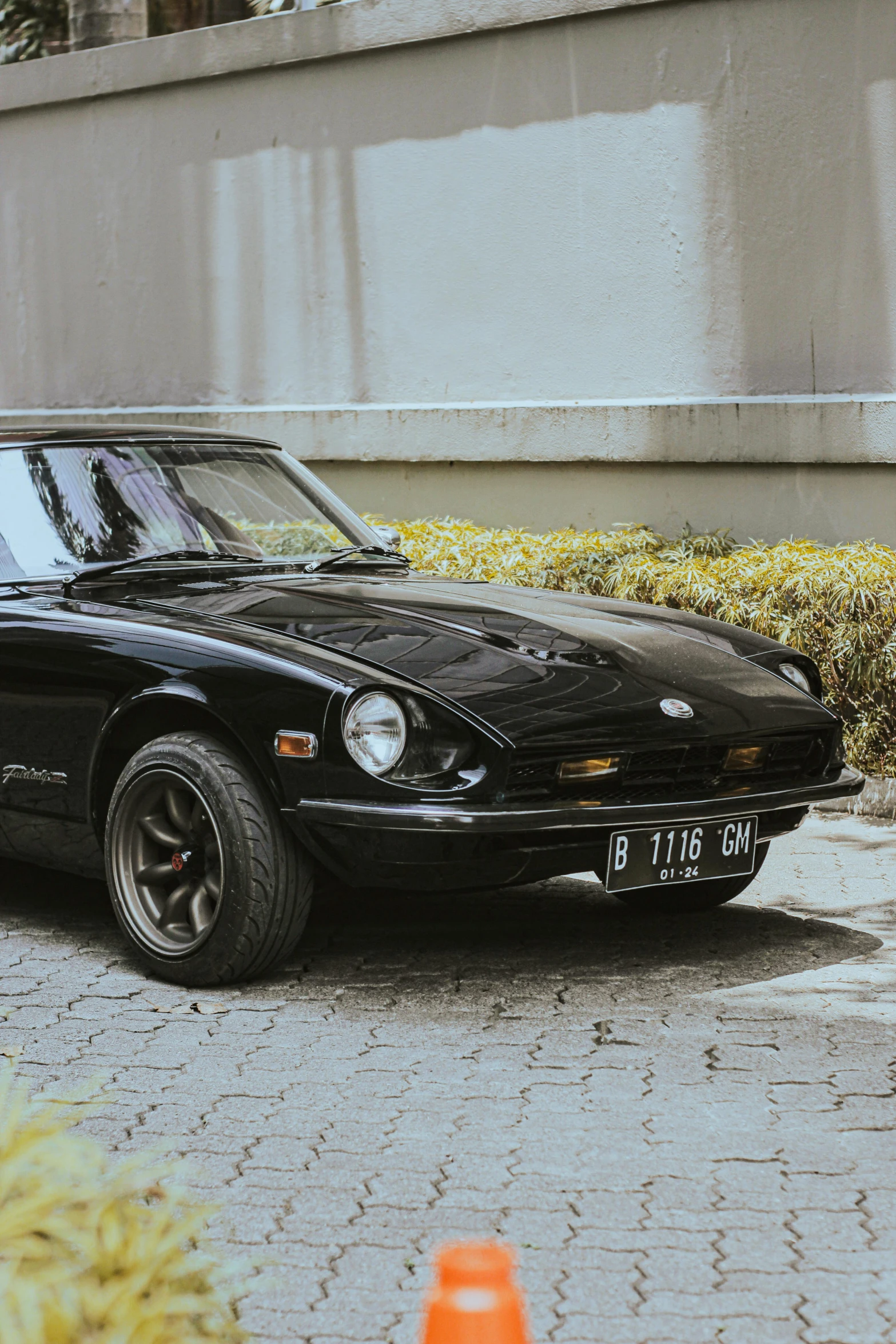 a black sports car is parked in front of a concrete wall