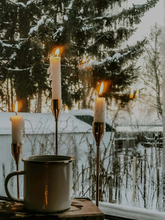 tealight candles sit on a window sill as the snow begins to fall