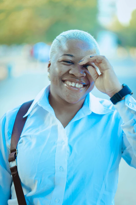 a woman in a blue shirt holds her hand to her face