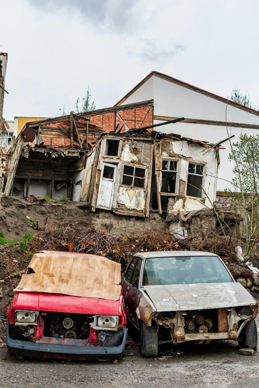 the two cars are sitting beside each other outside of the damaged buildings