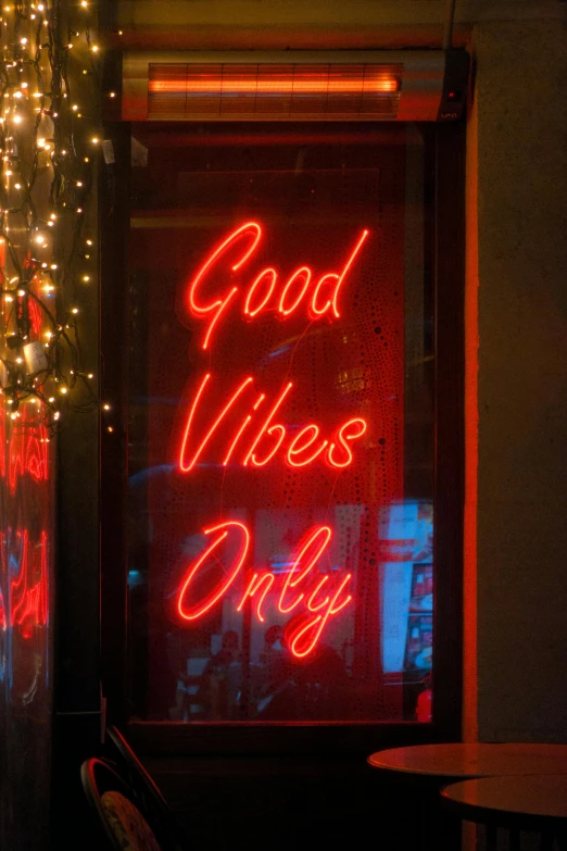a bright sign reads good vibes only against a black background
