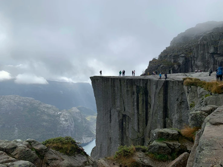 the people are walking on the edge of the cliff