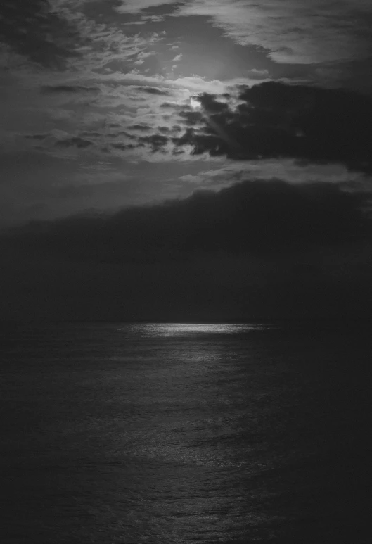 a black and white night scene with the moon in the distance