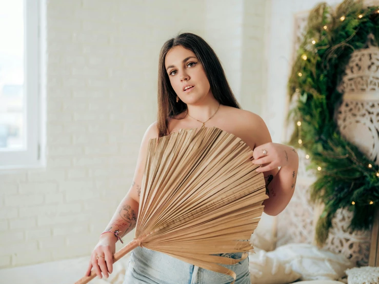 woman holding out hand fan in bedroom next to christmas wreath