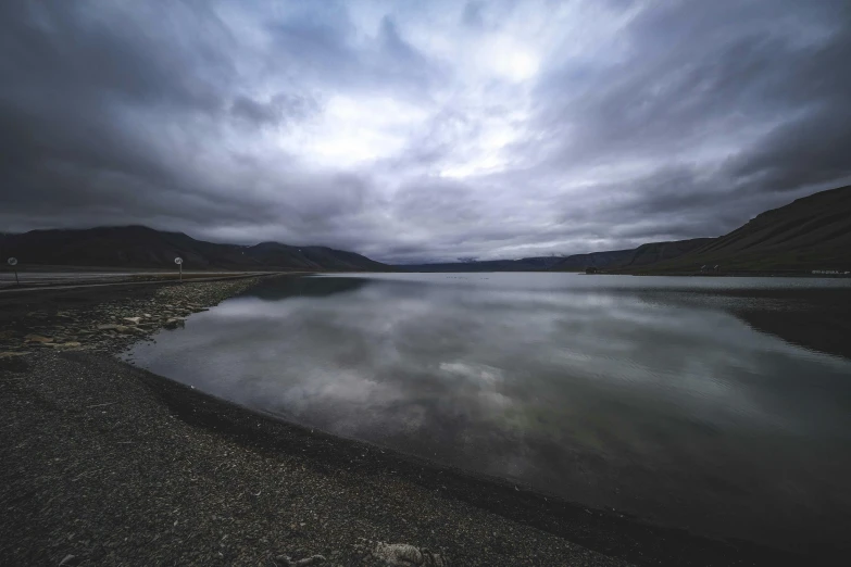 a lake that is under a cloudy sky