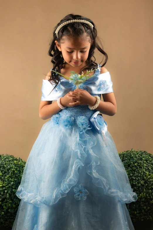  in blue dress looking down at flower