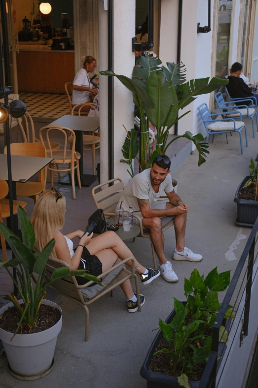 two people sitting at a restaurant with potted plants