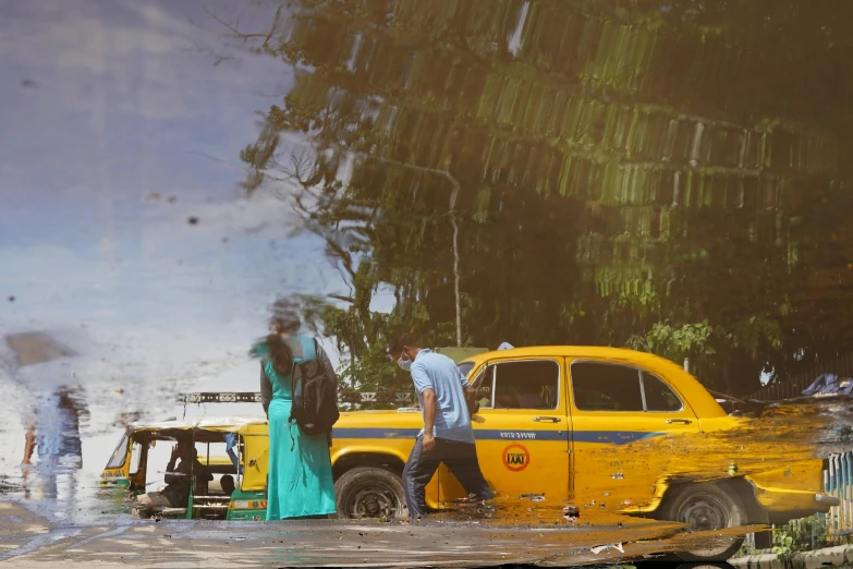 a man standing next to a yellow vintage truck