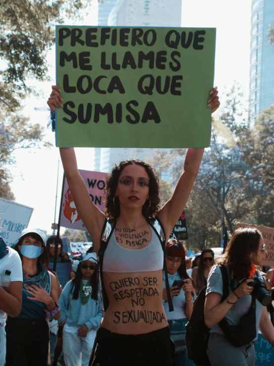 a woman is holding up a sign while standing on the street