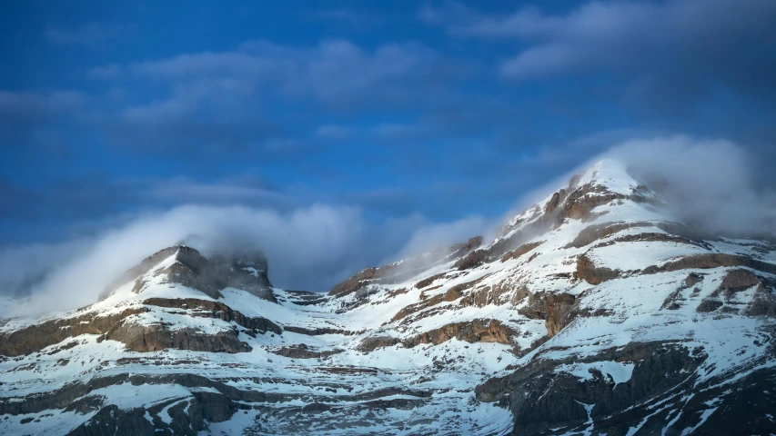 some snow covered mountains with a cloudy sky