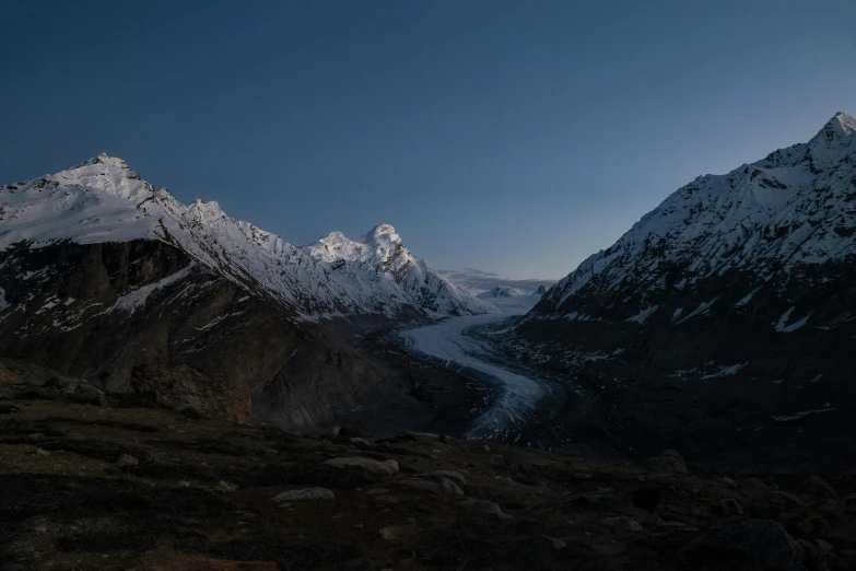 a river flowing between some very snowy mountains