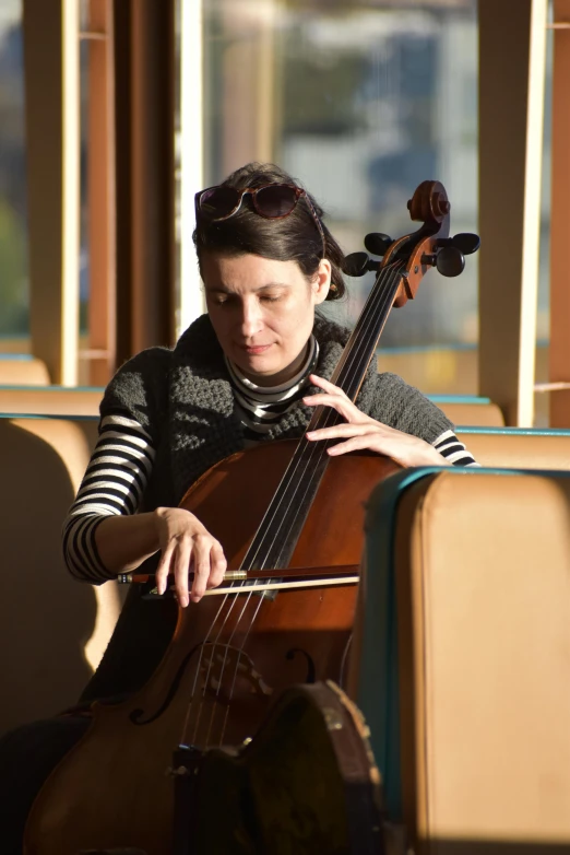 a woman is playing the cello and sitting