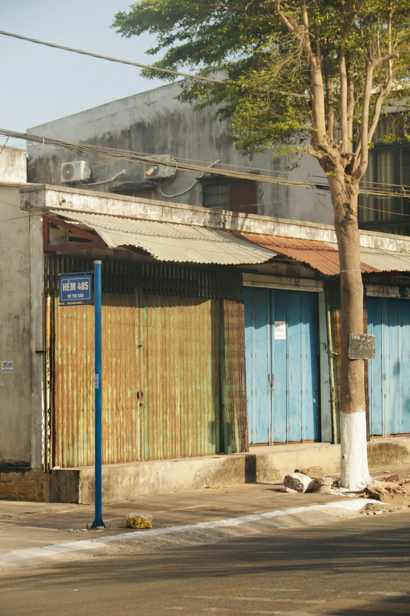 an old building with boarded up doors next to a tree