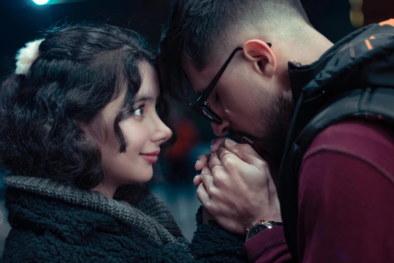 a man holding a woman's ear in the dark