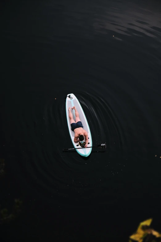 a person laying on a paddle board riding in the water