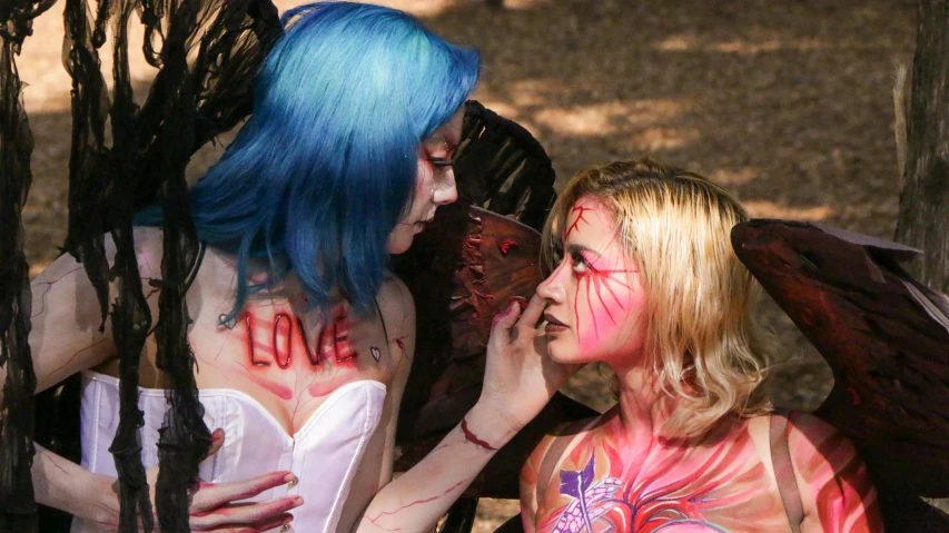 two woman with painted body paint look at a mirror