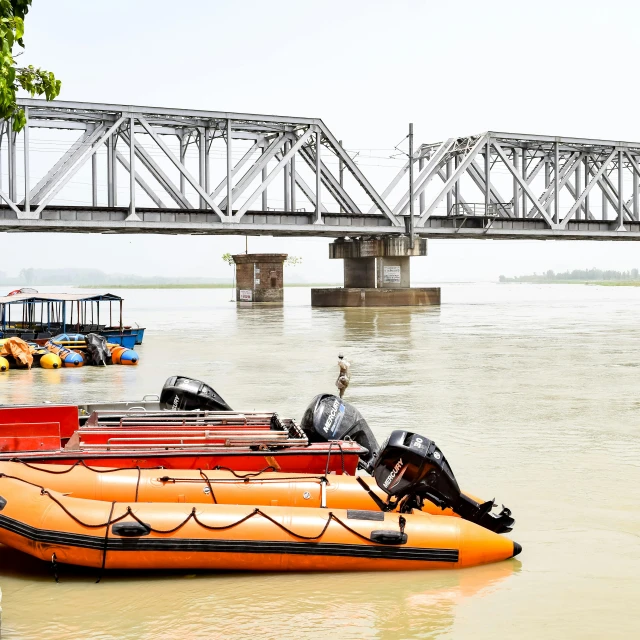 a group of boats floating along a river next to a bridge