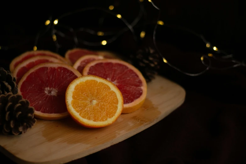 some oranges and some pine cones are sitting on a  board