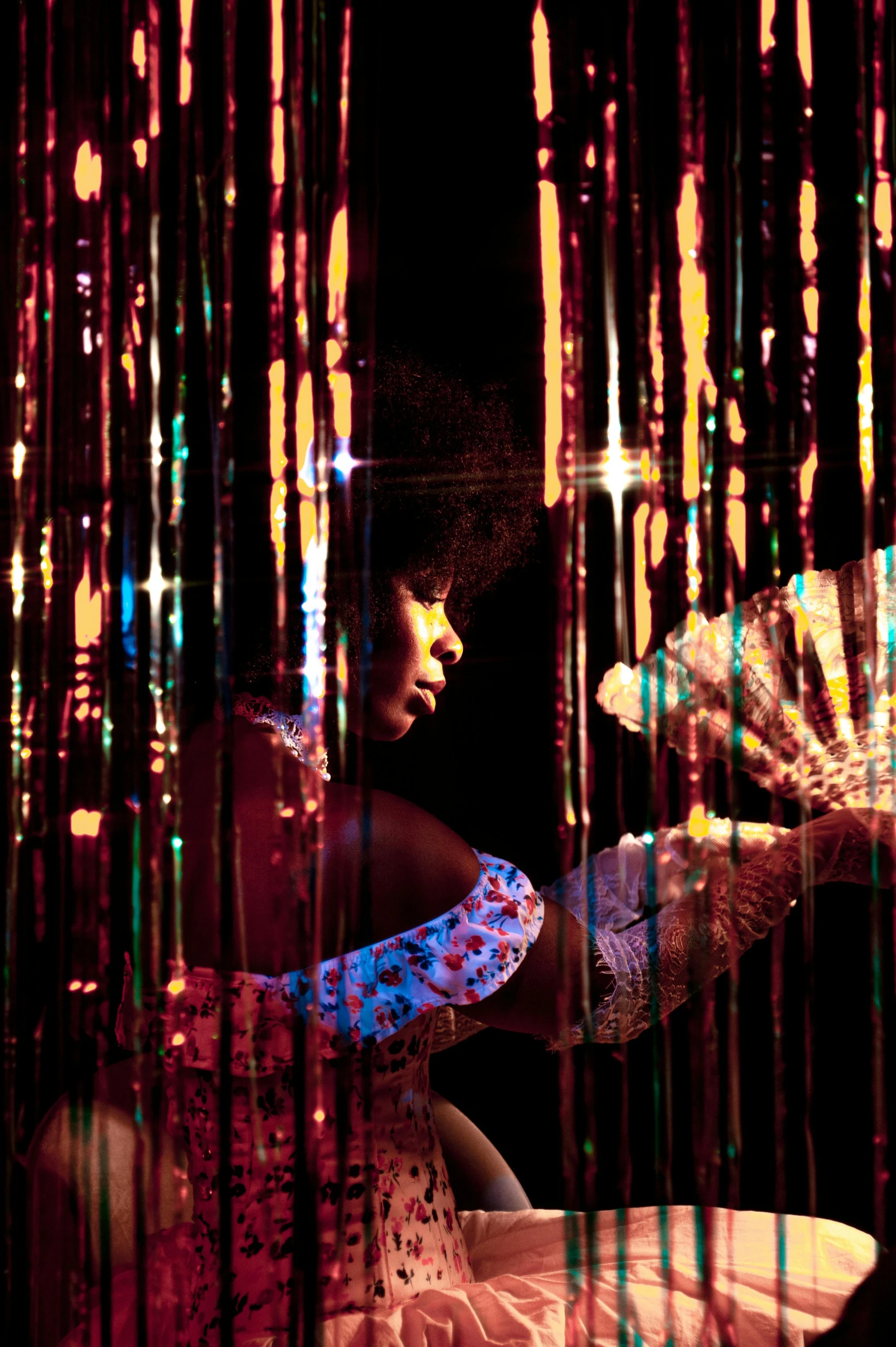 a woman sitting on top of a bed covered in pink and blue lights