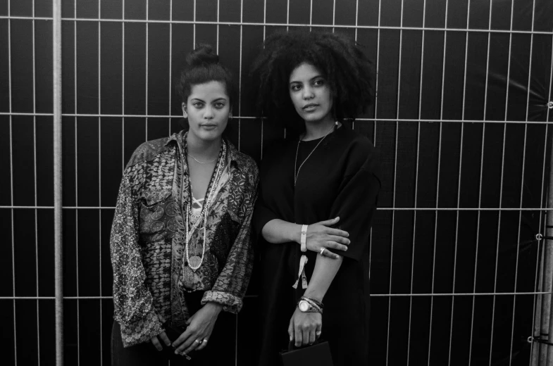 two women are posing together in front of a wall