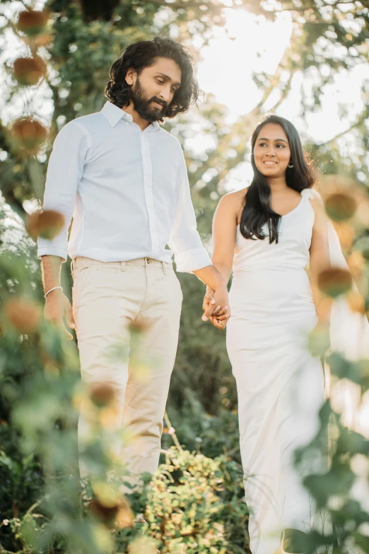 a bride and groom holding hands in front of a bunch of flowers