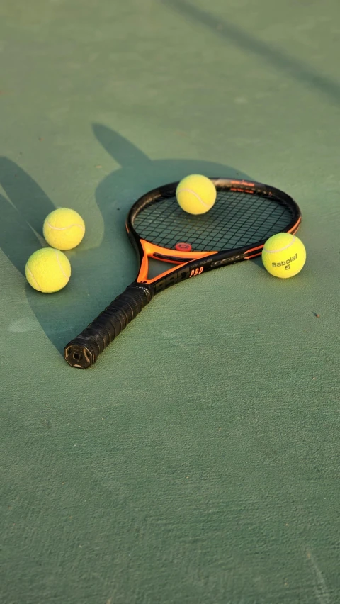 a tennis racket and three balls on the court