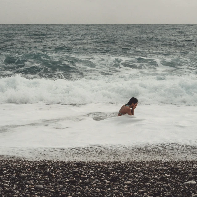 a woman standing in the waves on her surfboard