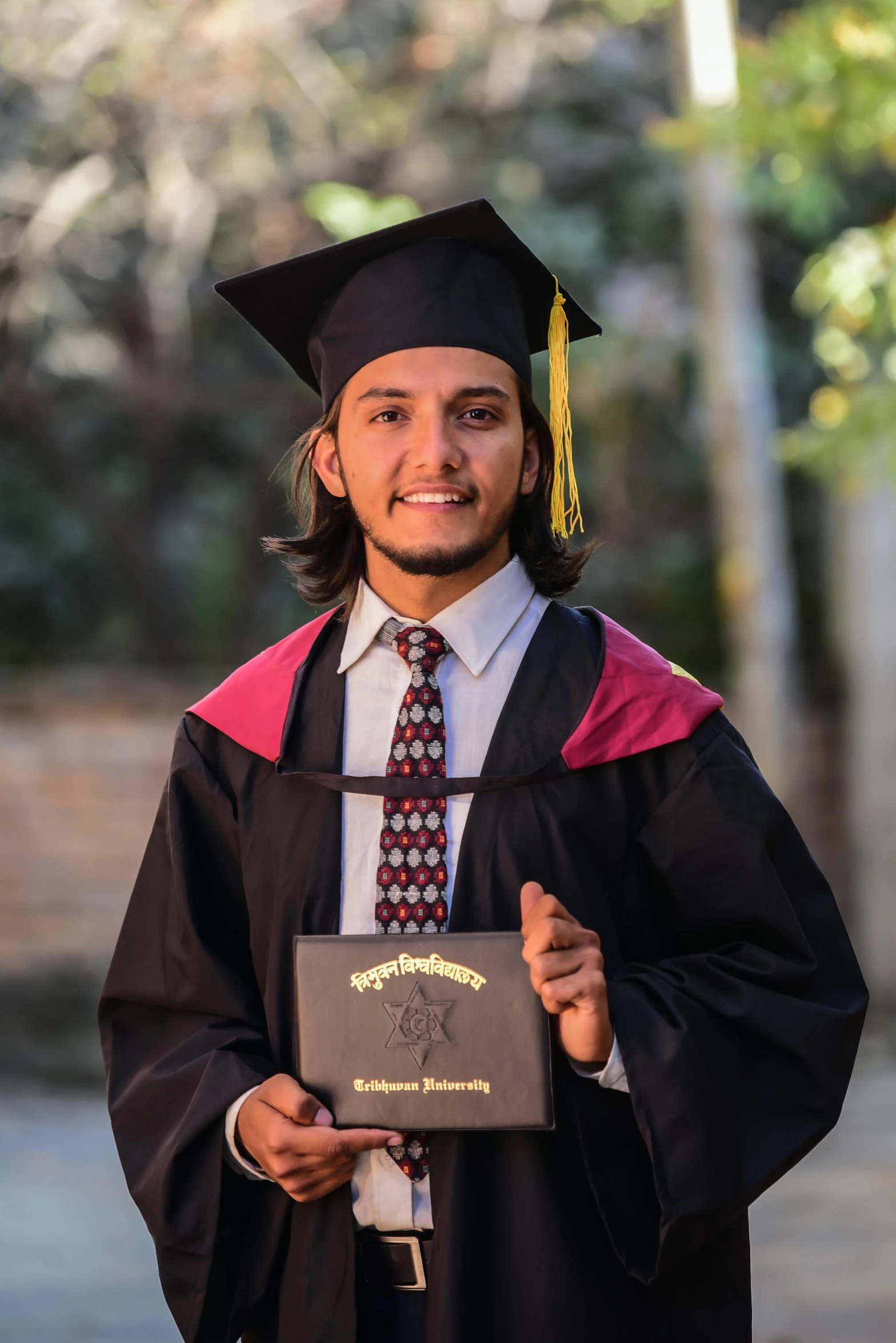 a young man poses with his diploma
