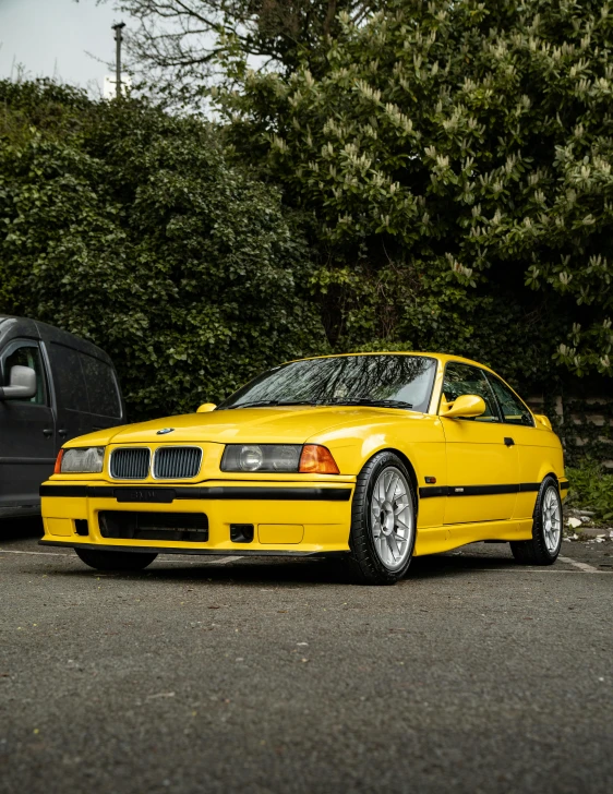 a yellow car sits in front of a parked van