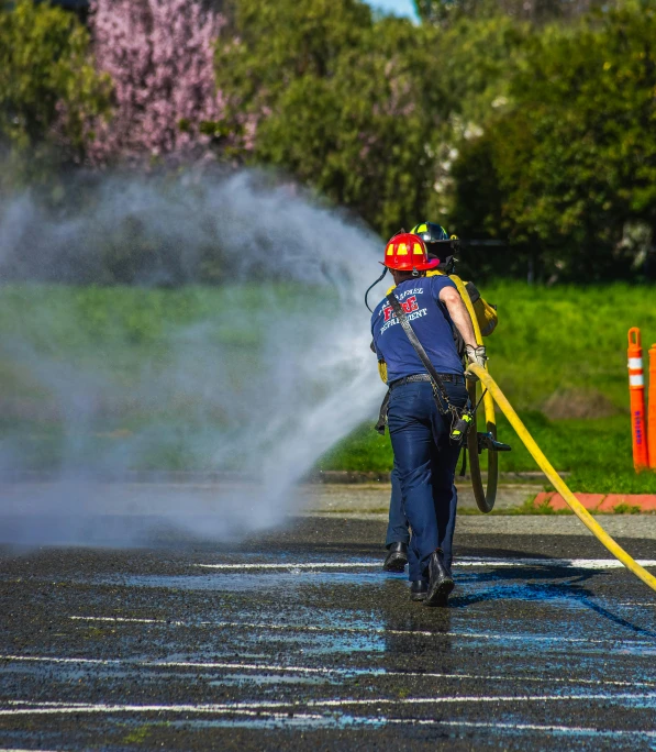 a fireman spraying water onto a street while wearing blue clothes
