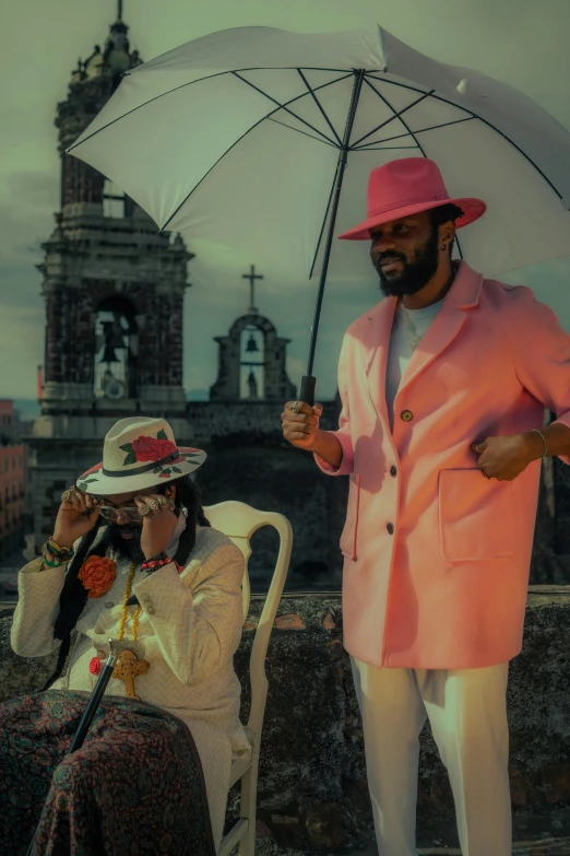 two people stand underneath an umbrella on the side of a wall