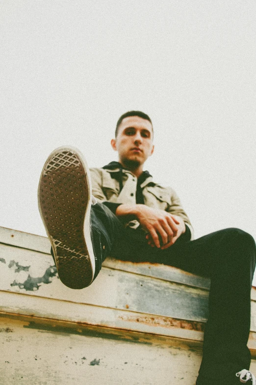 the young man is sitting on the ledge and posing