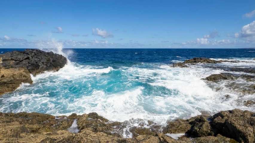 ocean waves breaking onto rocks on the shore