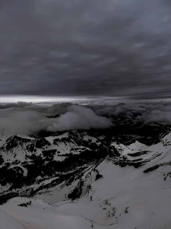 a mountain slope with snowy mountains under cloudy skies